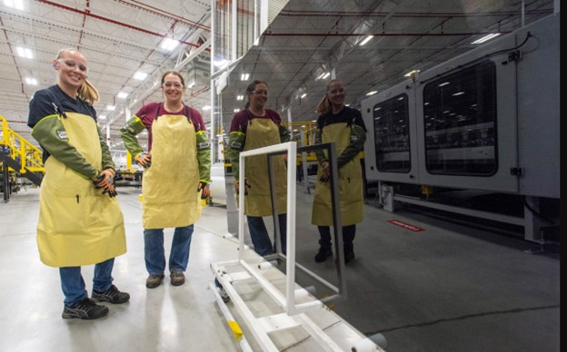 Workers show off a module at one of First Solar's plants. Image credit First Solar