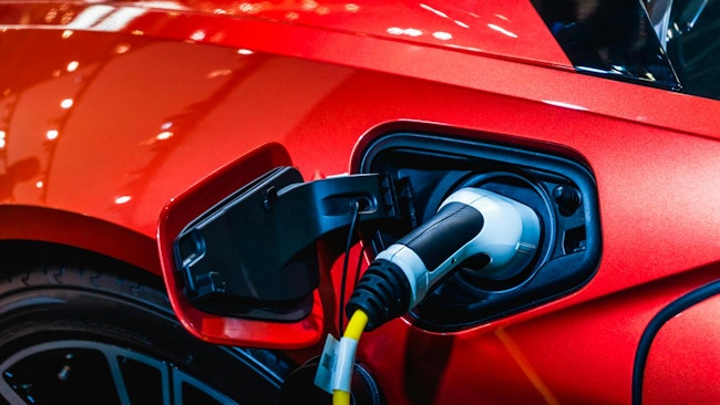 Close-up photo of a red electric car plugged in for charging.