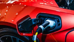 Close-up photo of a red electric car plugged in for charging. Close-up photo of a red electric car plugged in for charging.