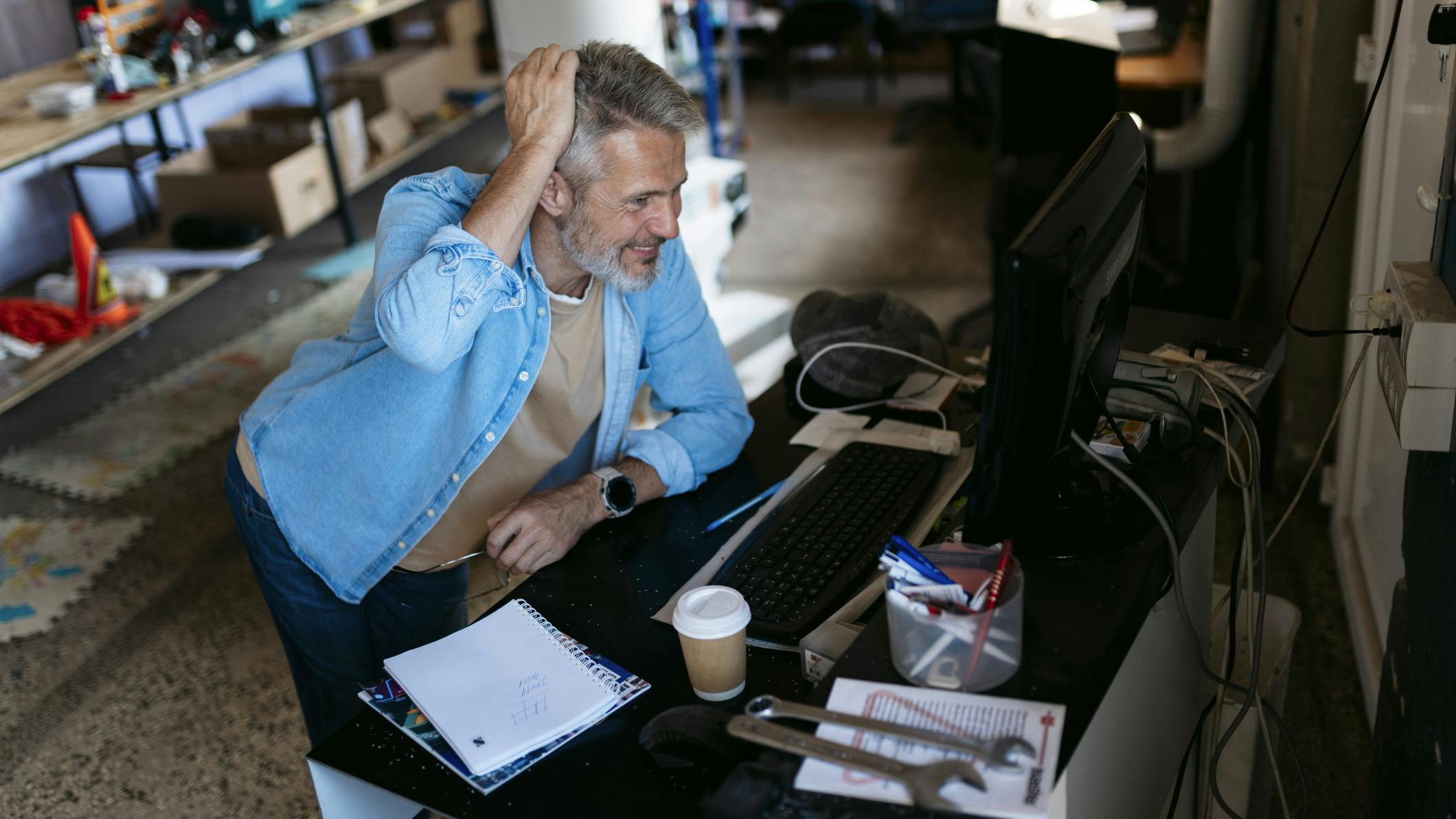 Engineer working on computer in messy workshop