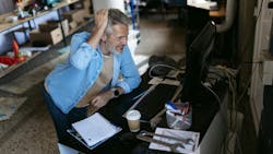 Engineer working on computer in messy workshop Engineer working on computer in messy workshop