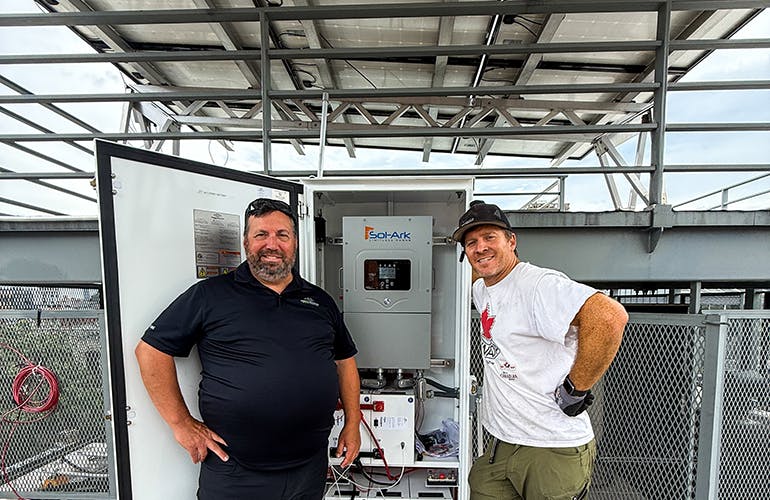 Brooklyn SolarWorks president Gaelen McKee and Brooke Plantz, business development manager for Briggs &amp; Stratton, pose beside the New York city residential battery project adjacent to the rooftop solar array. Image credit Brooklyn SolarWorks.