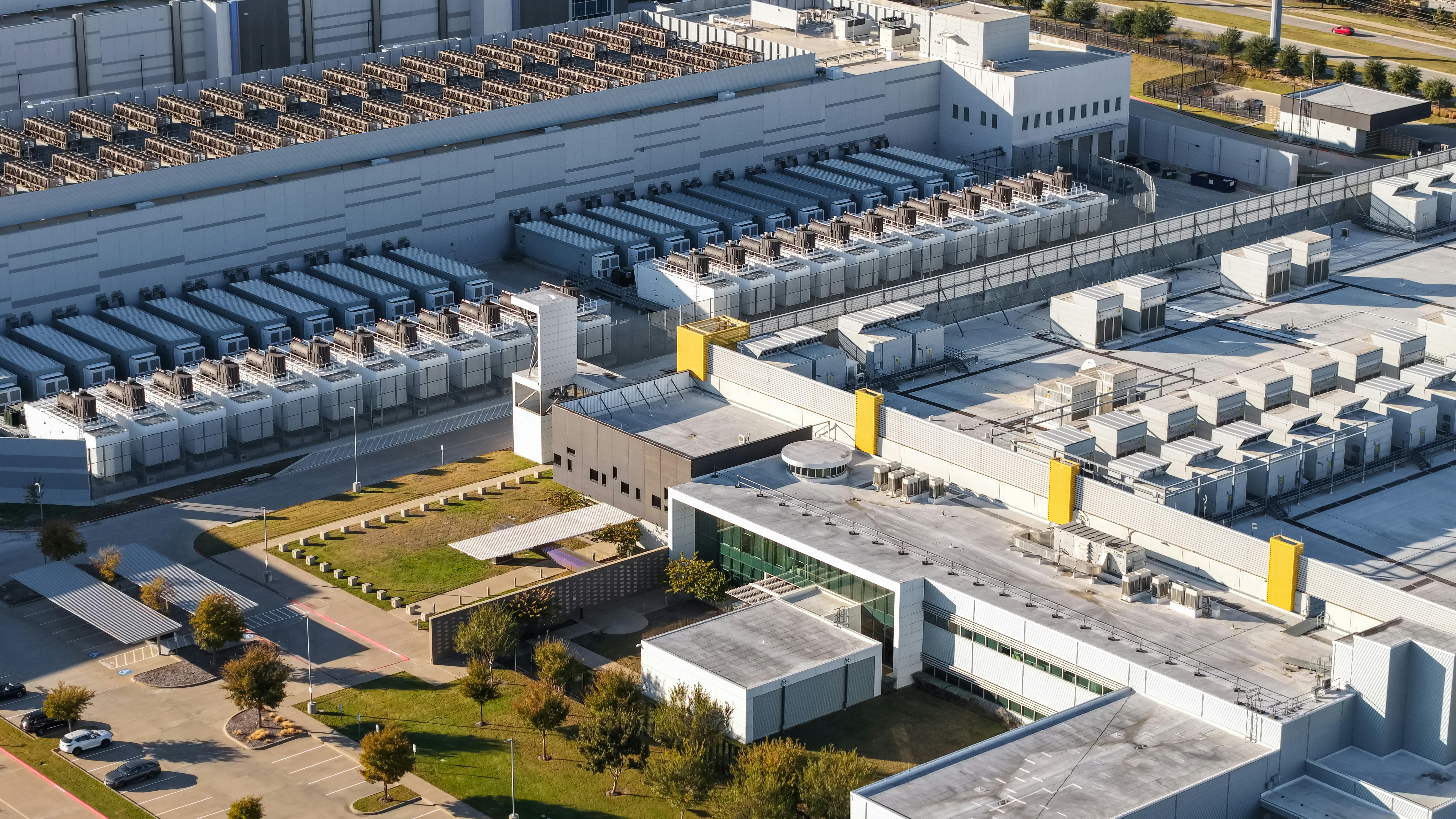Aerial view of large scale data center campus with server and cooling units.